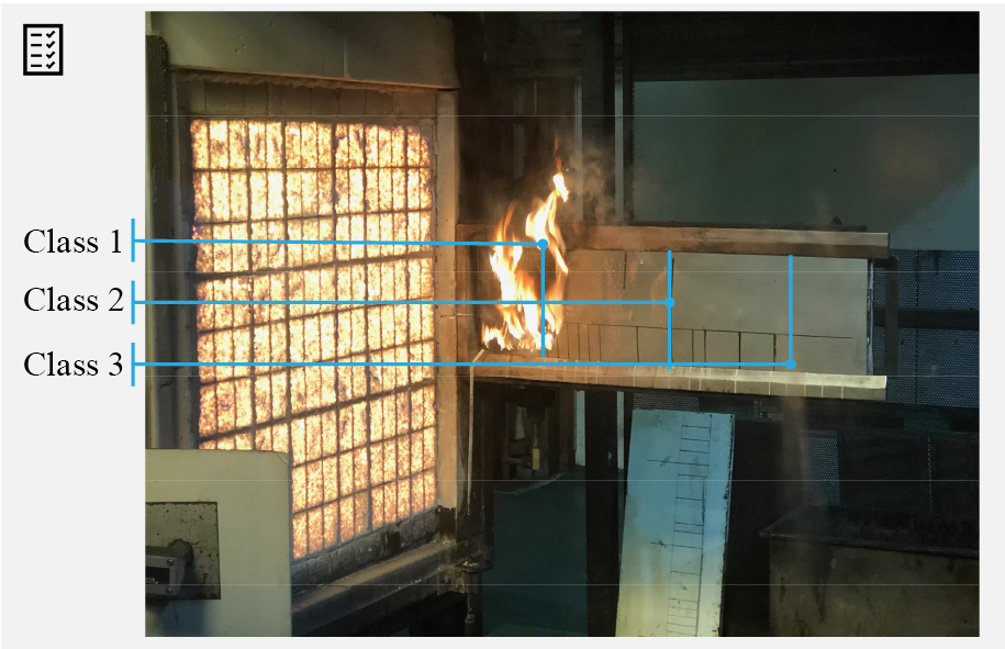 Photograph of a test in operation with a fire spreading horizontally along a measuring board.